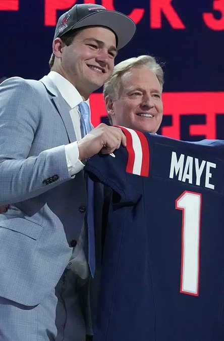 Drake Maye holding a custom jersey with his name and number alongside an official at an event.