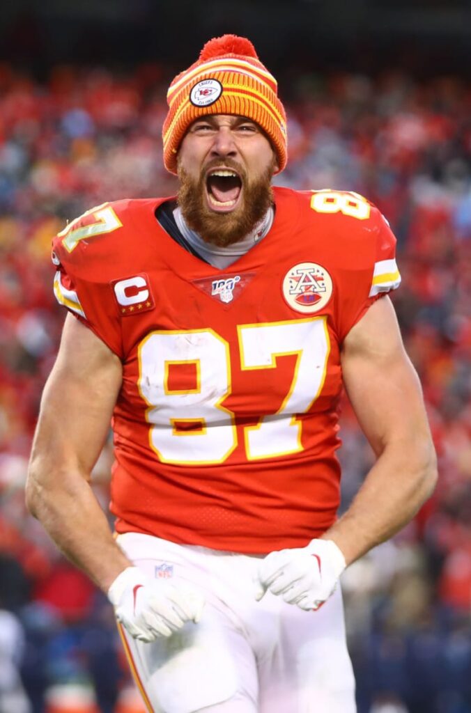 Travis Kelce celebrating in Kansas City Chiefs uniform, wearing a beanie